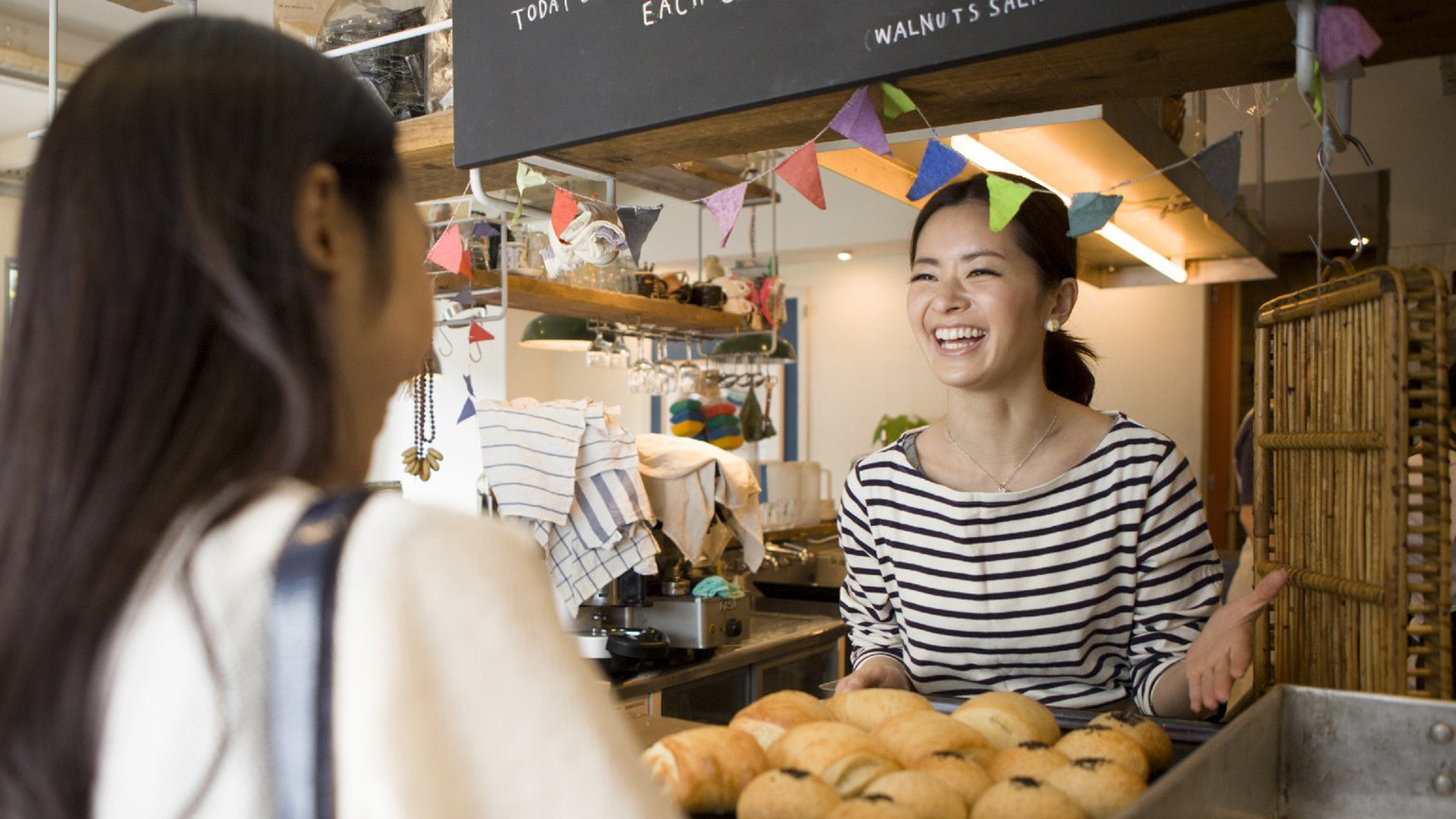 Women talking and laughing at bakery counter.